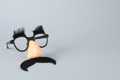 Photo of Funny mask with fake mustache, nose and glasses on grey background, space for text