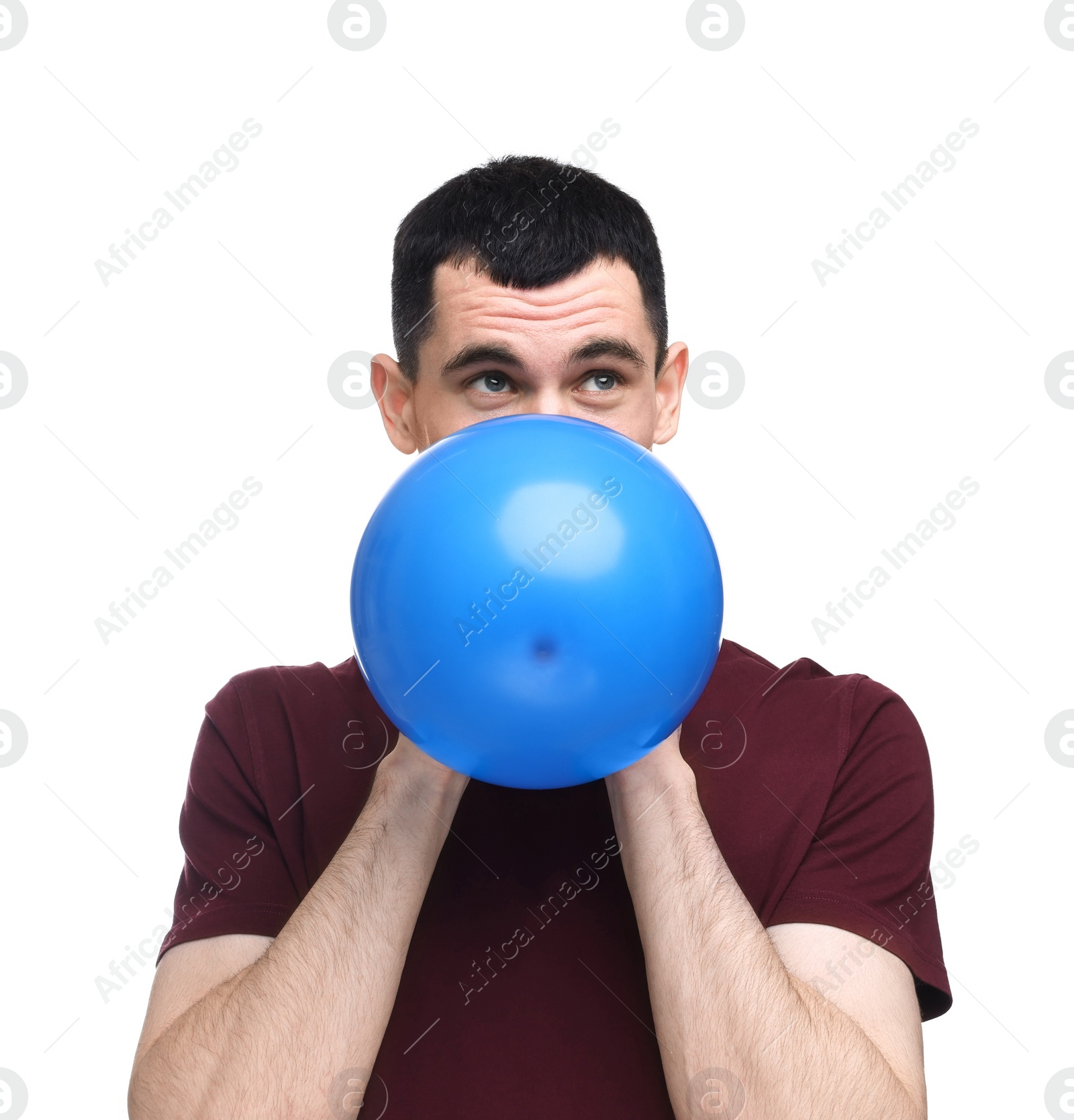 Photo of Young man inflating light blue balloon on white background