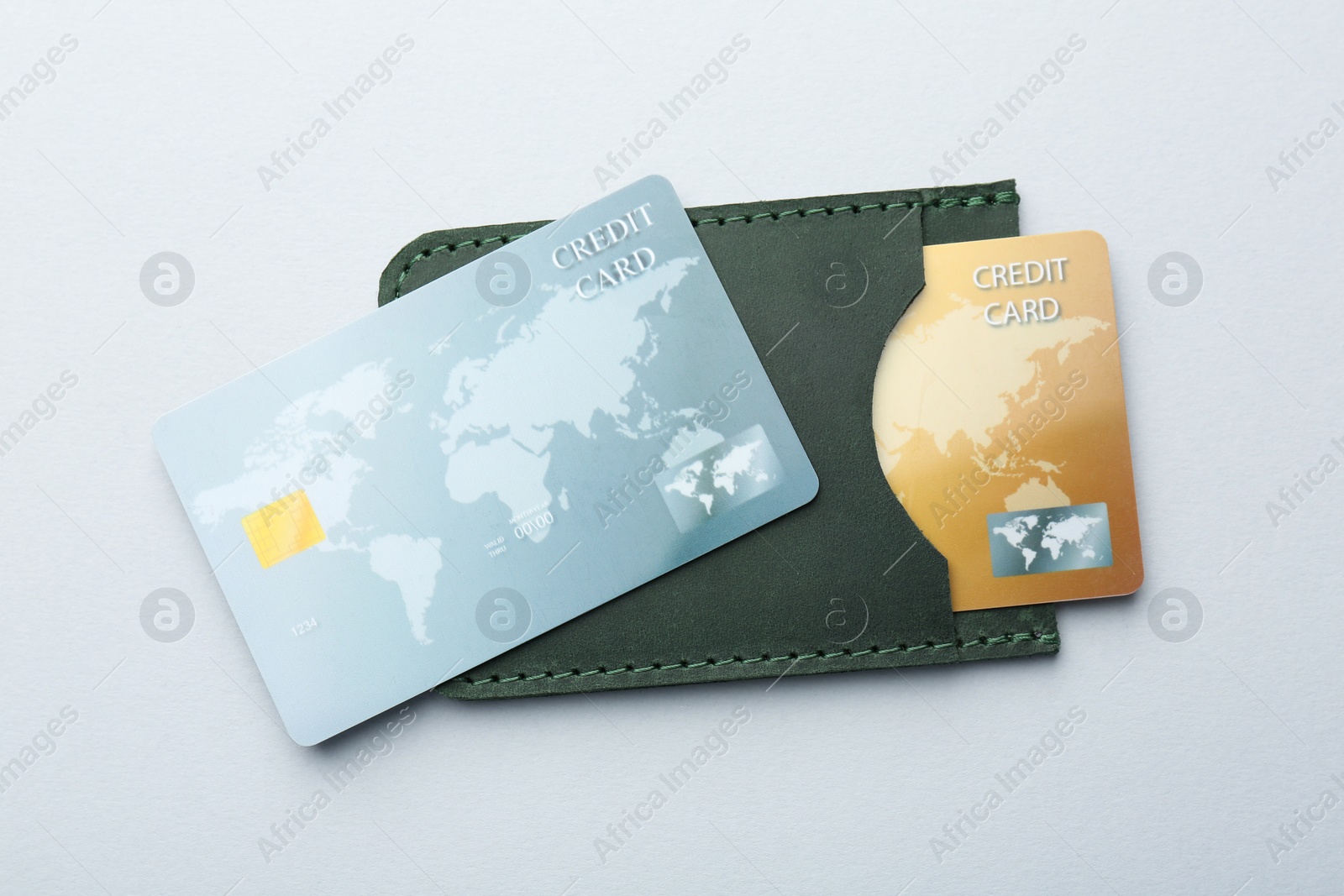 Photo of Woman holding leather card holder with credit cards on light grey background, top view