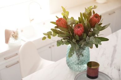 Photo of Bouquet with beautiful protea flowers on table in kitchen, space for text. Interior design