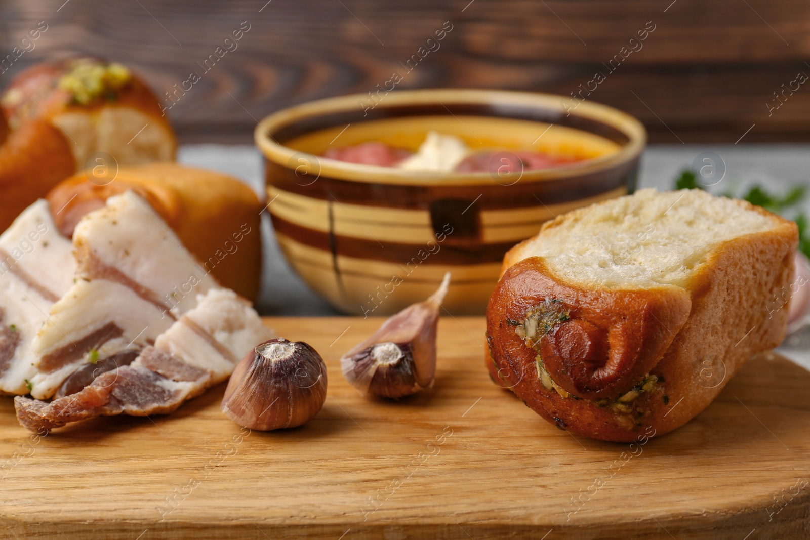 Photo of Delicious pampushky (buns with garlic) and salo served for borsch on table, closeup. Traditional Ukrainian cuisine