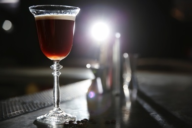 Photo of Glass of martini espresso cocktail on bar counter. Space for text