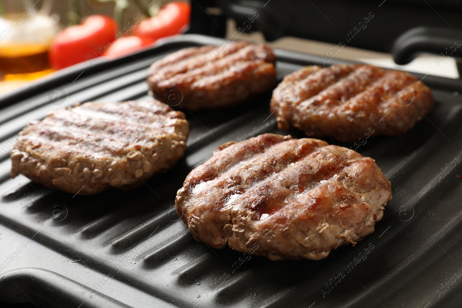 Photo of Delicious hamburger patties cooking on electric grill, closeup