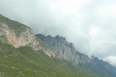 Picturesque landscape with high mountains and fog under gloomy sky