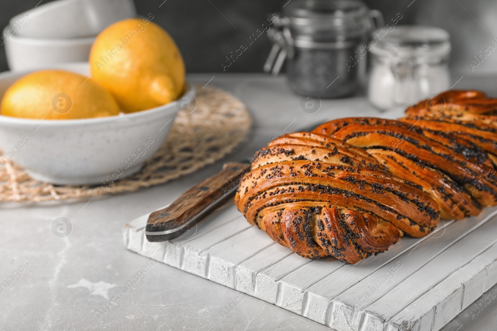 Photo of Tasty sweet bun with poppy seeds on gray table