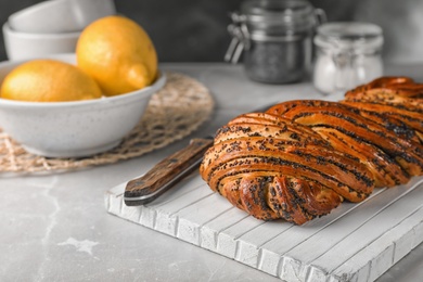 Tasty sweet bun with poppy seeds on gray table