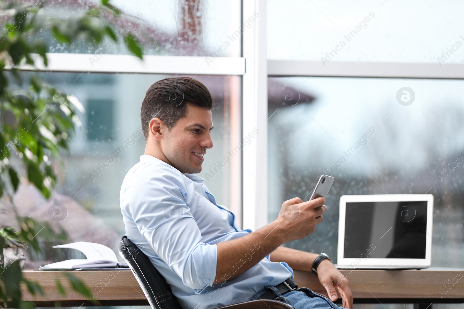 Photo of Businessman using smartphone in office chair at workplace