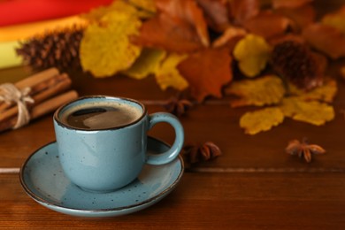 Photo of Composition with cup of hot coffee and autumn leaves on wooden table, space for text