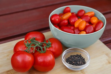 Photo of Bowl with fresh tomatoes and spices on wooden table