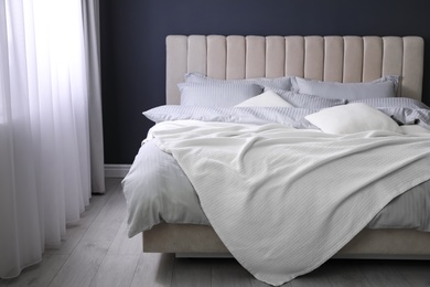 Photo of Comfortable bed with soft blanket and pillows indoors