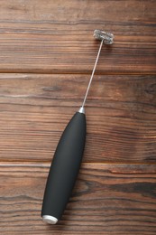 Photo of Black milk frother wand on wooden table, top view