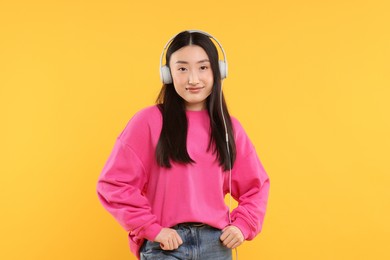 Portrait of beautiful woman in headphones on orange background