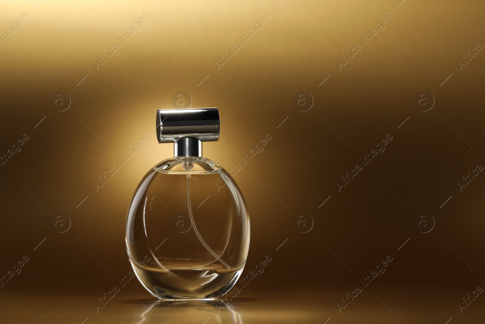 Photo of Luxury women's perfume. Sunlit glass bottle on golden background, space for text