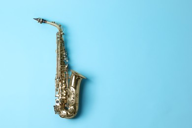 Photo of Beautiful saxophone on light blue background, top view. Space for text