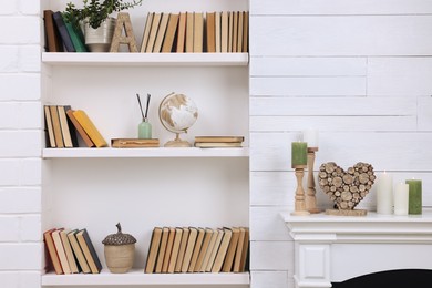 Photo of Collection of books and decor elements on shelves indoors