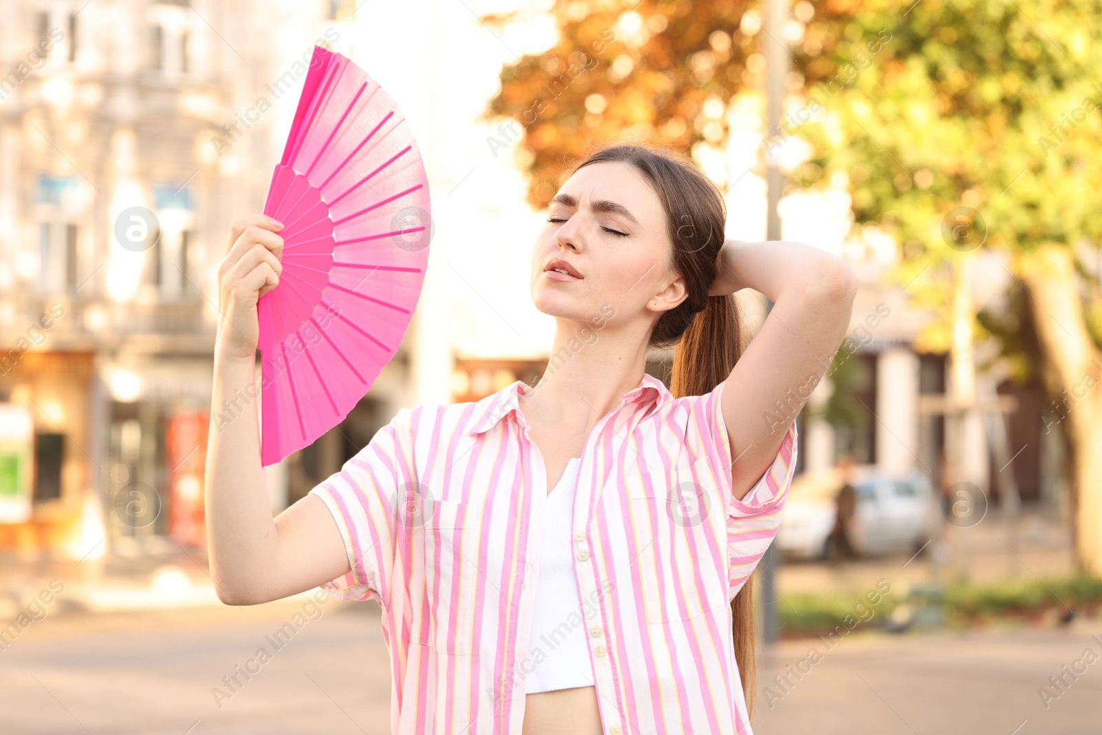 Photo of Woman with hand fan suffering from heat outdoors