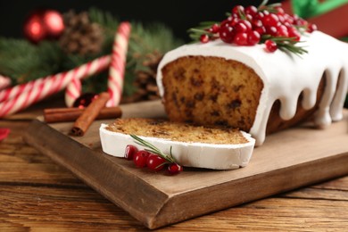 Traditional classic Christmas cake decorated with cranberries, pomegranate seeds and rosemary on wooden table