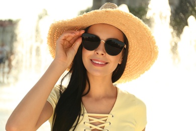 Photo of Beautiful young woman wearing stylish sunglasses outdoors