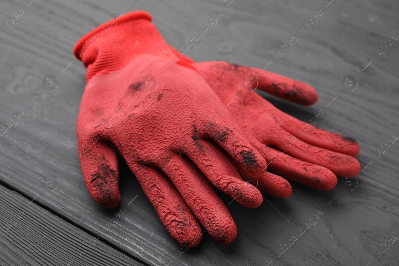 Photo of Pair of red gardening gloves on grey wooden table, closeup