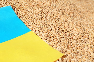 Photo of National flag of Ukraine on wheat grains, closeup. Global food crisis concept
