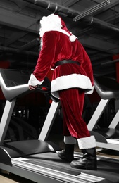 Photo of Authentic Santa Claus training on treadmill in modern gym