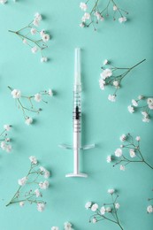 Photo of Cosmetology. Medical syringe and gypsophila flowers on turquoise background, flat lay