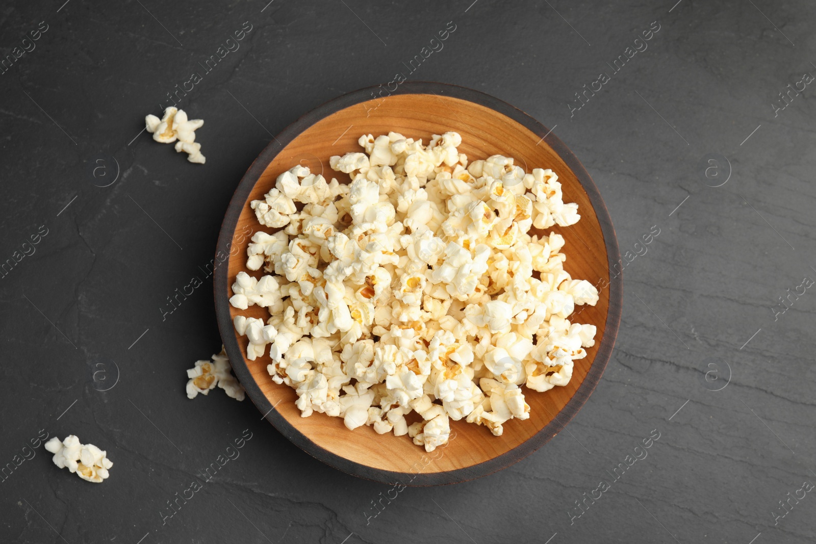 Photo of Tasty fresh pop corn on black table, flat lay