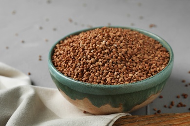 Photo of Uncooked buckwheat in ceramic bowl on table