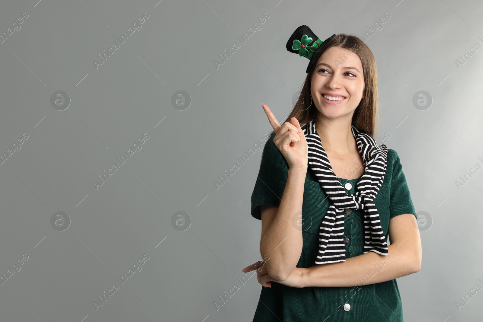 Photo of Happy woman in St Patrick's Day outfit on light grey background, space for text