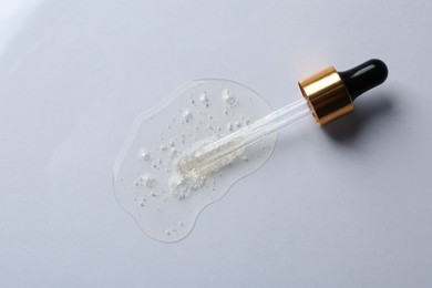 Pipette with cosmetic serum on white background, top view