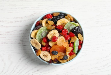 Bowl with different dried fruits on wooden background, top view. Healthy lifestyle