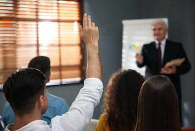 Photo of People raising hands to ask questions at seminar in office