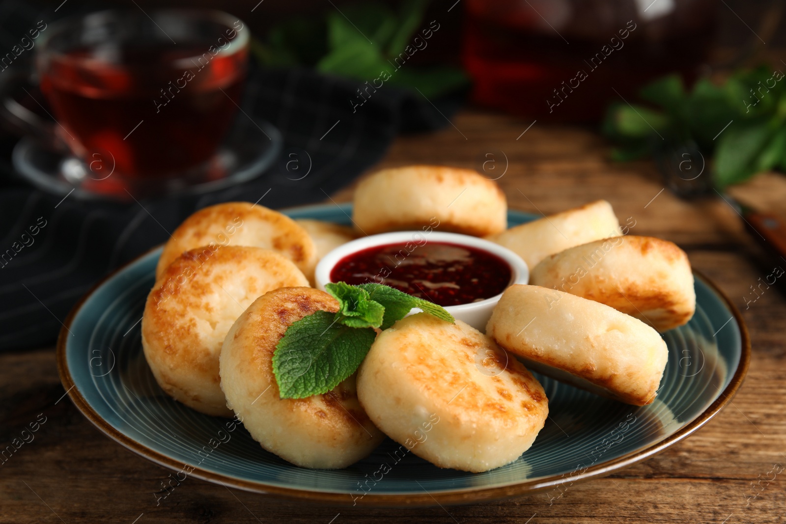 Photo of Delicious cottage cheese pancakes with jam and mint on wooden table