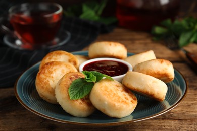 Photo of Delicious cottage cheese pancakes with jam and mint on wooden table