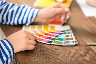 Photo of Female designer working with color palette samples at table