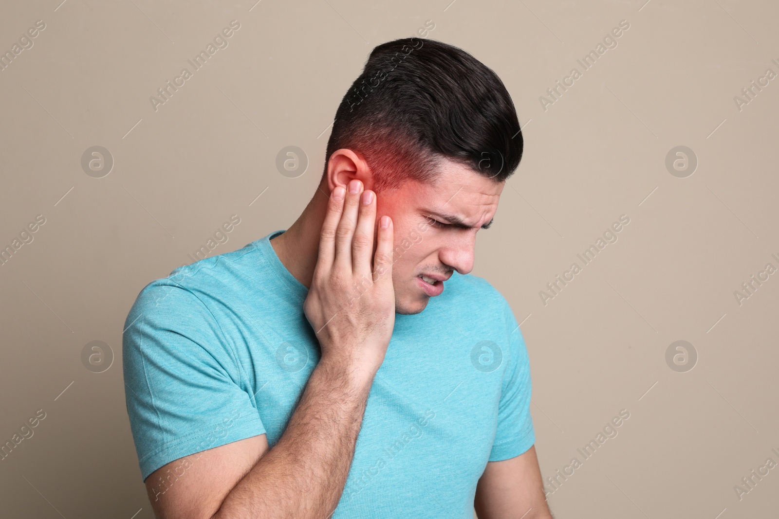 Image of Man suffering from ear pain on beige background