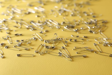 Many new safety pins on yellow background