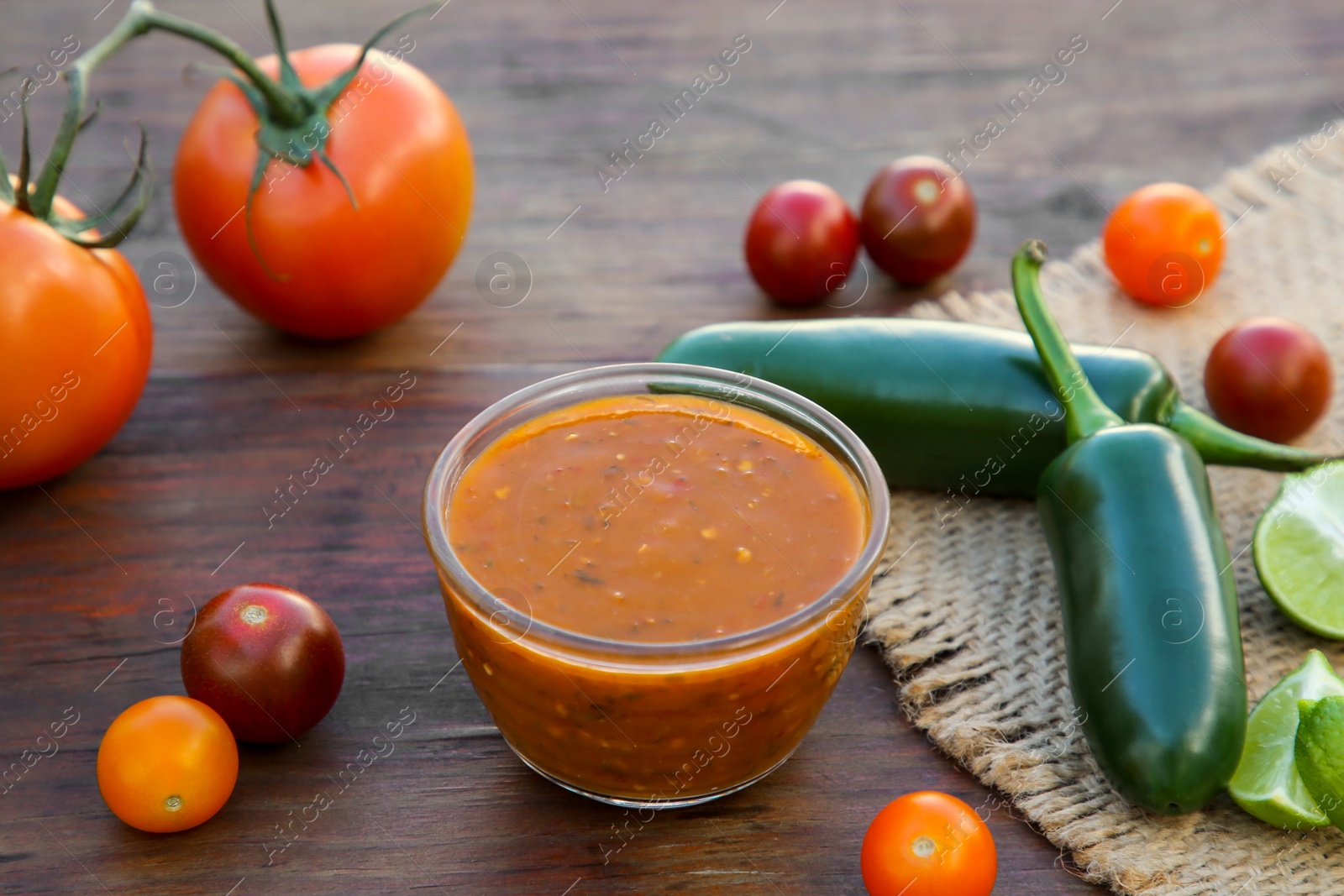 Photo of Tasty salsa sauce and ingredients on wooden table, closeup