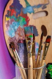 Photo of Brushes with colorful paints and wooden artist's palette