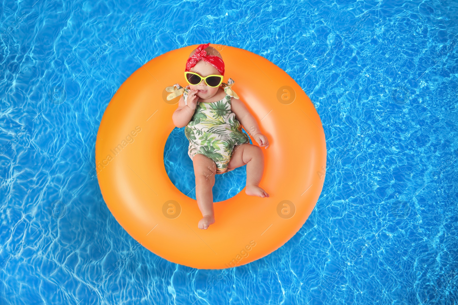 Image of Cute little baby with inflatable ring in swimming pool, top view