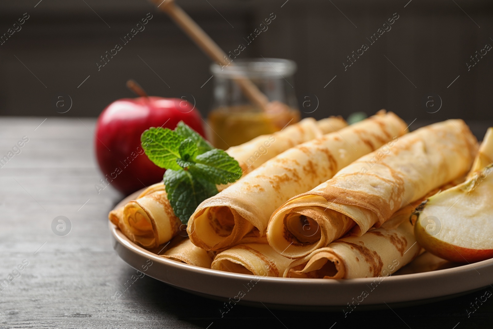 Photo of Delicious rolled thin pancakes on wooden table