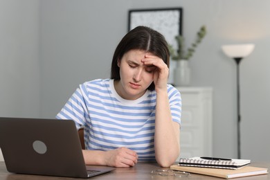 Photo of Overwhelmed woman sitting with laptop at table indoors