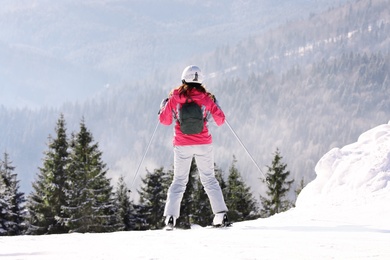 Woman skiing on snowy hill in mountains. Winter vacation