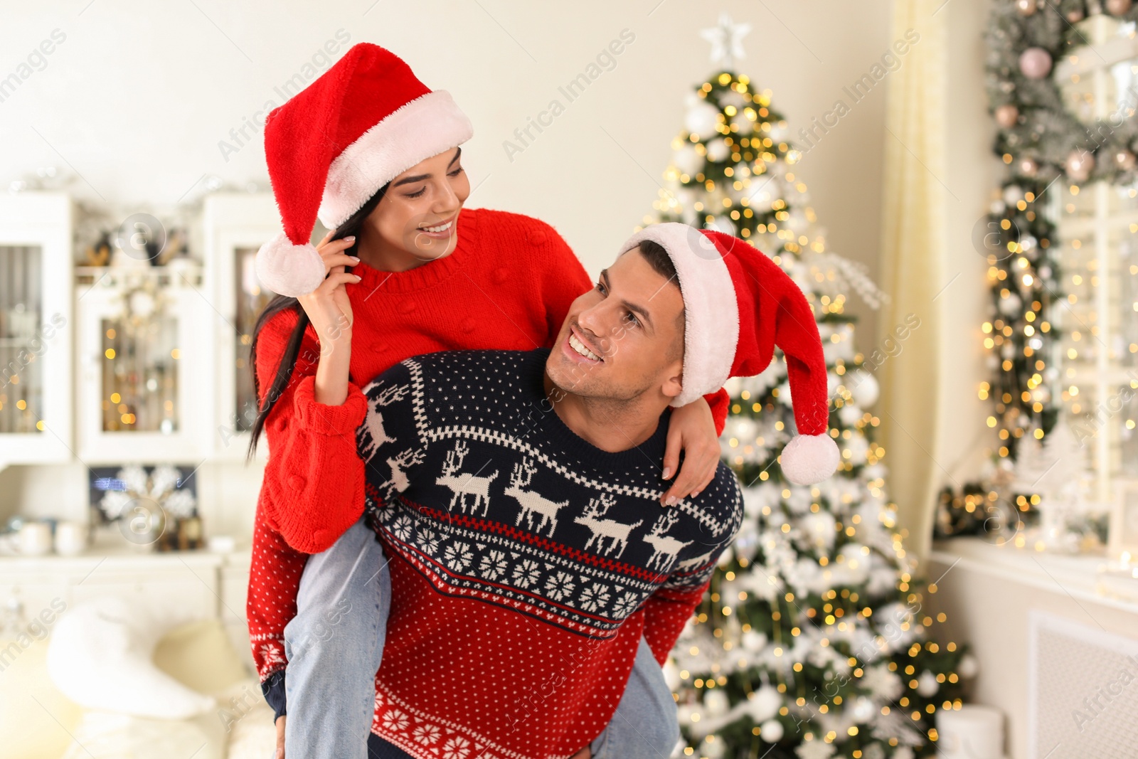 Photo of Happy couple in Santa hats having fun at home. Christmas celebration