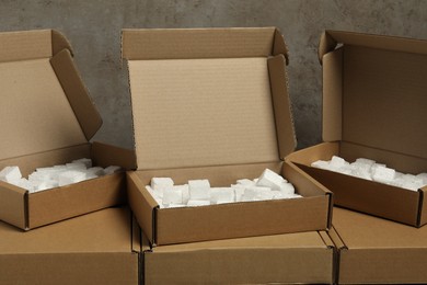 Photo of Many closed and open cardboard boxes with pieces of polystyrene foam on grey textured background