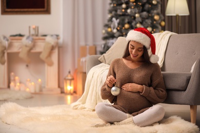 Photo of Happy pregnant woman with Christmas ball at home. Expecting baby