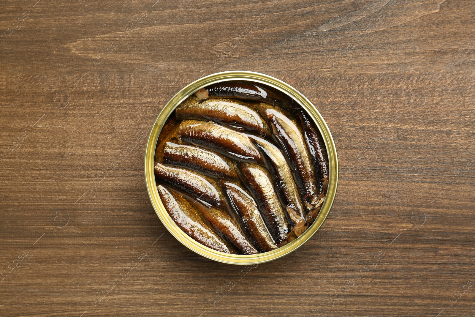 Photo of Sprats in tin can on wooden table, top view