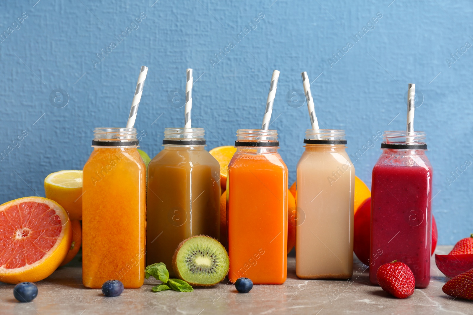 Photo of Bottles with healthy detox smoothies and ingredients on table