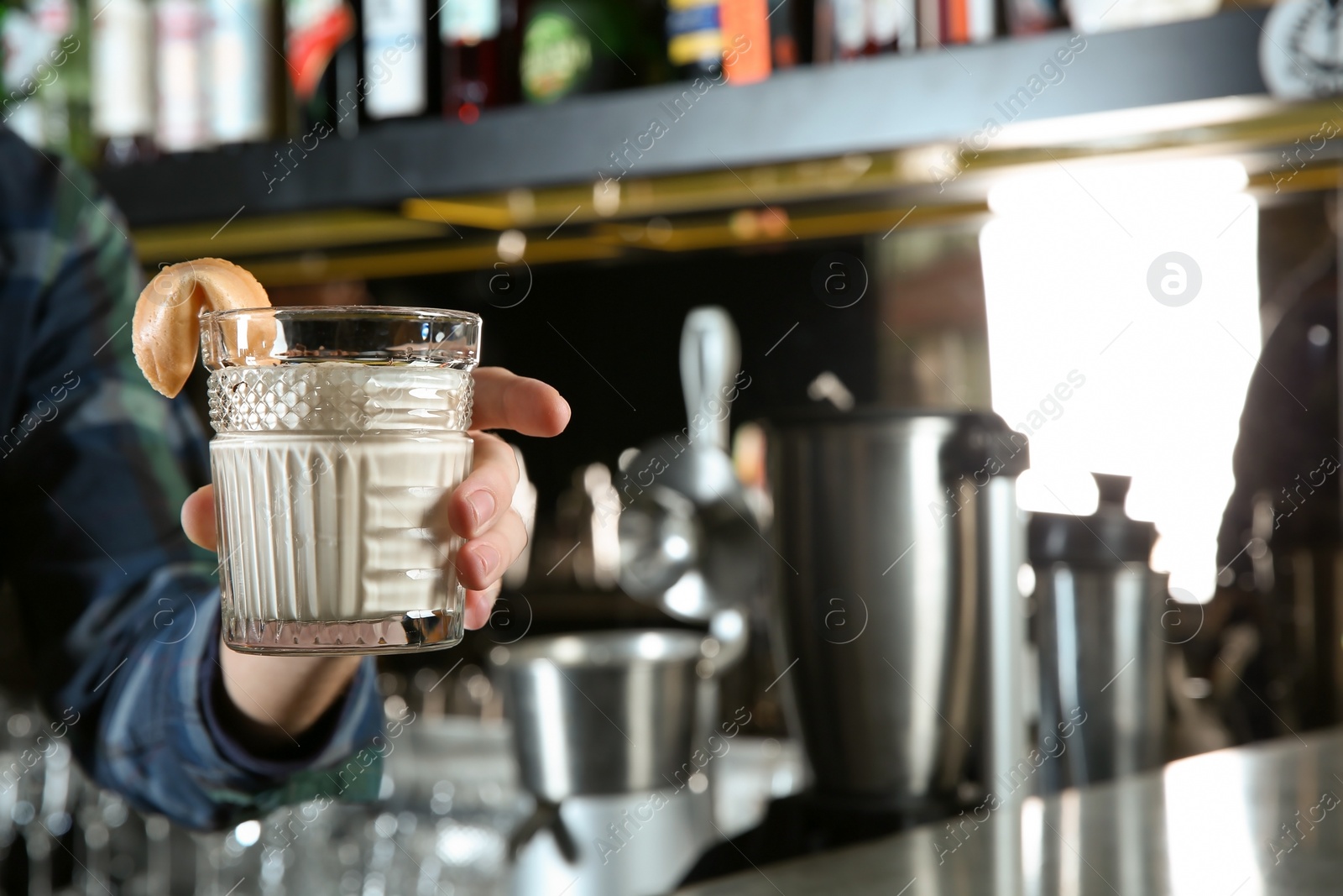 Photo of Barman holding fresh alcoholic White Russian cocktail in pub, closeup. Space for text