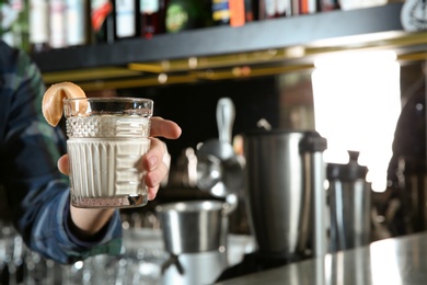 Photo of Barman holding fresh alcoholic White Russian cocktail in pub, closeup. Space for text